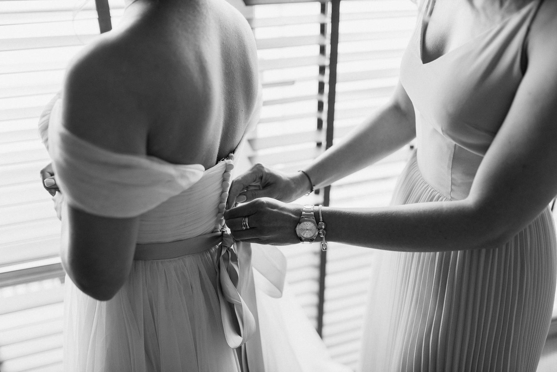 Intimate black and white shot of wedding preparation with bride and bridesmaid.